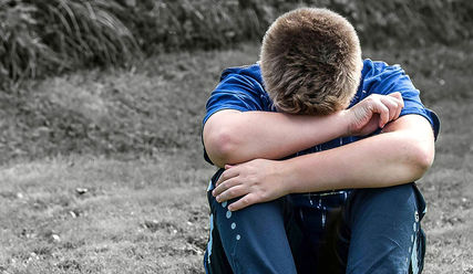 Ein Kind vergräbt seinen Kopf traurig in seinen Armen - Copyright: © Creative Commons, CC0