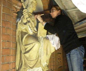 Eine Restauratorin reinigt die Apostelfigur