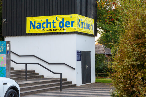 KIrchturmsockel mit Banner "Nacht der Kirchen 2024"